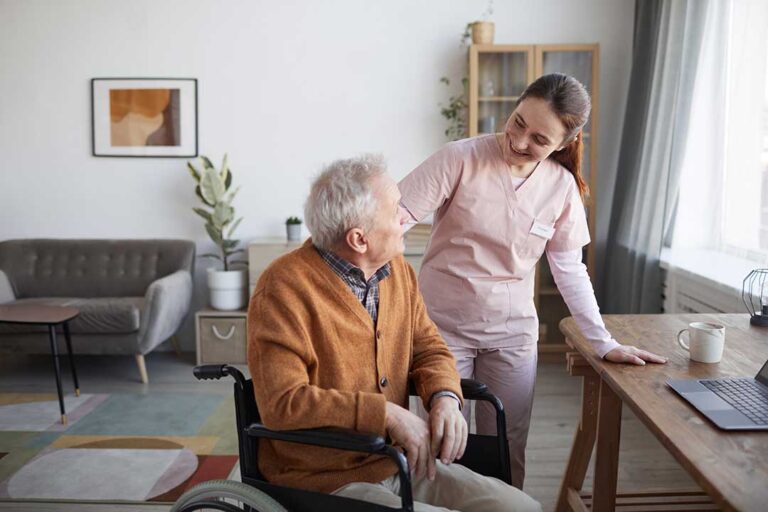 Two older adults walking down a wide hallway with handrails, talking and smiling.