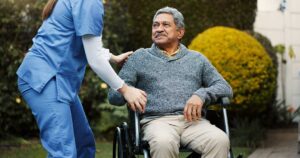 Older adults sharing a friendly conversation around a table in a bright assisted living common room.
