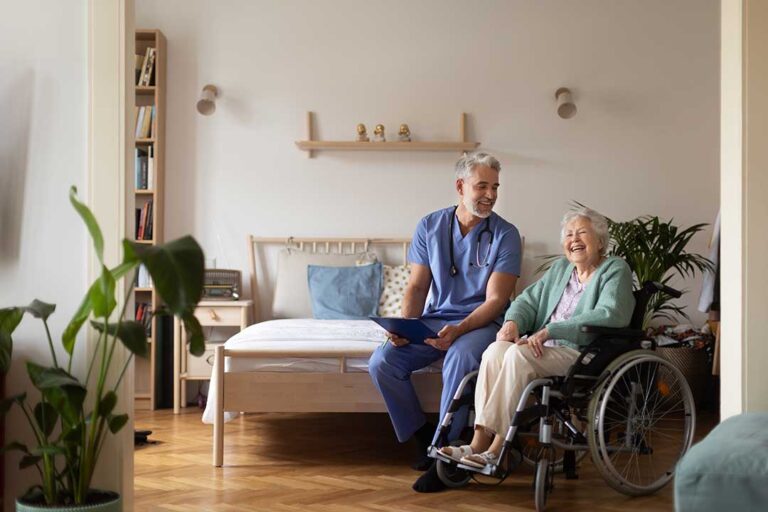 A group of older adults sharing a meal at a large table in a bright, home-like dining room.